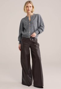Grå stickad kofta med guldfärgade knappar kombinerad med höga bruna vida byxor i konstläder. Mjuk textur och avslappnad passform.