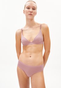 Light pink lingerie set featuring a bralette with thin adjustable straps and matching low-rise briefs, made from smooth fabric with minimal seams.