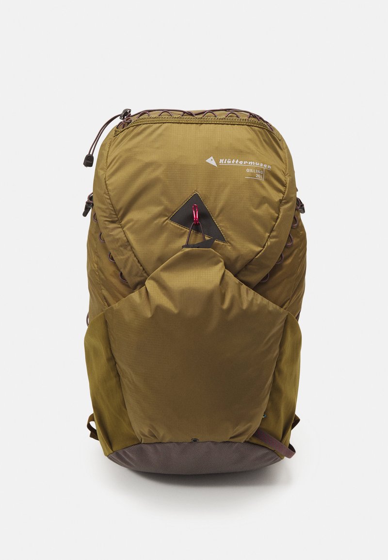 Green nylon backpack with a triangular gray patch, top zipper closure, side pockets, and adjustable straps. Features a carabiner for attachment.