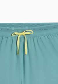 Short en sarcelle avec détail de taille perforée et cordon jaune noué au centre devant.