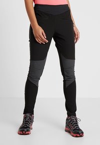 Černé sportovní kalhoty s šedými síťovinovými panely a zipovými kapsami. Mají přiléhavý design a pružnou látku pro pohodlí. V kombinaci s turistickými botami.