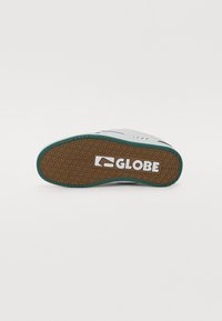 Shoe sole featuring a tread pattern with a brown base, teal accents, and a white logo. Smooth texture with durable materials.