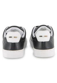 Μαύρα δερμάτινα αθλητικά παπούτσια με λευκές ελαστικές σόλες και επενδυμένους αστραγάλους. Διαθέτουν μινιμαλιστικό σχεδιασμό με ομαλή υφή και διακριτικές λεπτομέρειες.