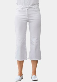 Witte cropped jeans met een aansluitende taille, vijf-pocket ontwerp en subtiele stiksels. Gecombineerd met lichtgekleurde instappers.