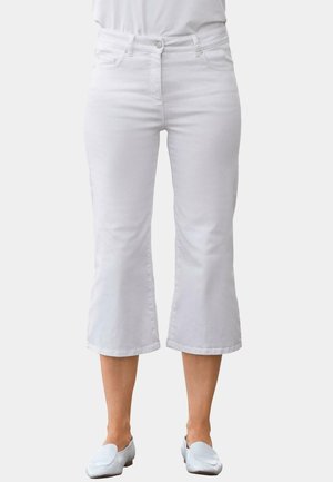Weiße, cropped Jeans mit einer taillierten Taille, fünf Taschen Design und subtilen Nähten. Kombiniert mit hellen Slippern.