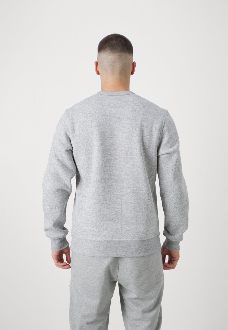 Sudadera gris de manga larga, con puños y dobladillo acanalados, textura suave, cuello redondo estándar y diseño sencillo, combinada con pantalones grises a juego.