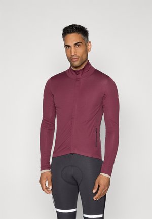 Bordeauxfarbene Fahrradlederjacke mit langen Ärmeln, hohem Kragen, schmaler Passform und seitlicher Reißverschlusstasche; kombiniert mit schwarzen Radhosen mit reflektierenden Akzenten.