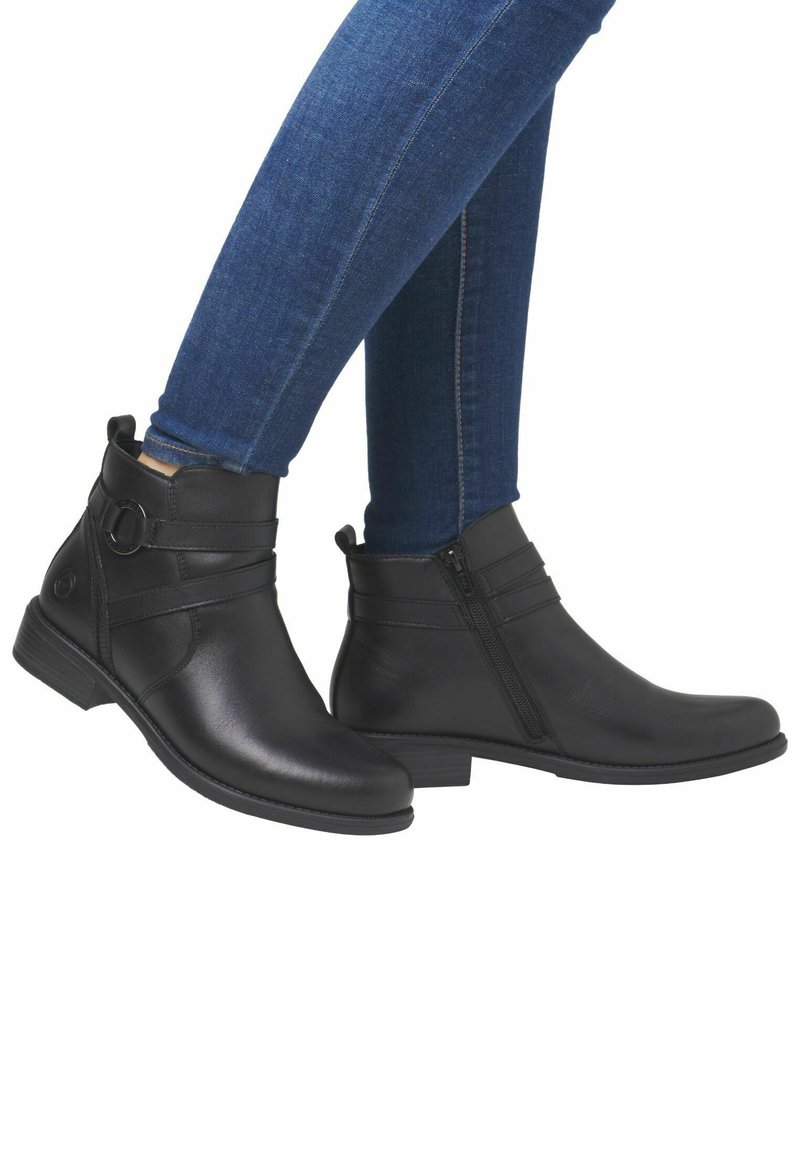 Bottines en cuir noir avec fermeture éclair sur le côté, deux sangles horizontales, petit talon et finition texturée, présentées aux côtés d'un jean bleu.