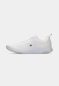 Chaussures de sport blanches avec une tige texturée, un matériau en maille légère, des accents réfléchissants et un design de semelle à motifs.