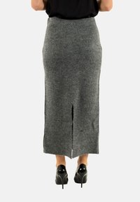 Gonna grigia in misto lana di lunghezza media con spacco posteriore e vita aderente. Abbinata a tacchi alti in pelle verniciata.