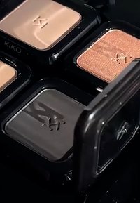 Vier KIKO oogschaduwschotels in beige, zwart, koper en tan tinten in een zwart compact doosje.