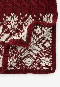 Rote und cremefarbene gestrickte Wurfdecke mit einem strukturierten Kabelmuster und geometrischen Designs, mit einem gefalteten Rand, der komplexe Details zeigt.