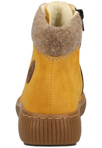 Bottine en cuir jaune avec un col en feutre marron, fermeture éclair sur le côté, semelle en caoutchouc marron texturé et détail de logo circulaire sur le côté.