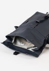 Dunkelblauer Rolltop-Rucksack mit offenem Hauptfach, das das hellgraue Innere und eine innere Reißverschlusstasche zeigt.