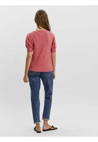 Pink knitted sweater with short puff sleeves, paired with rolled cuff blue jeans and black flip-flops, viewed from the back.