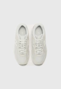 Baskets blanches de sport avec tissu en maille, bout rond, languette rembourrée et logo discret. Les lacets et les accents texturés améliorent la stabilité.