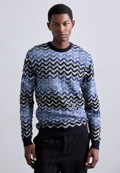 Maglione lavorato a maglia con motivo a onde in blu, nero e bianco. Collo e polsini a coste, texture liscia, forma rotonda e maniche lunghe.
