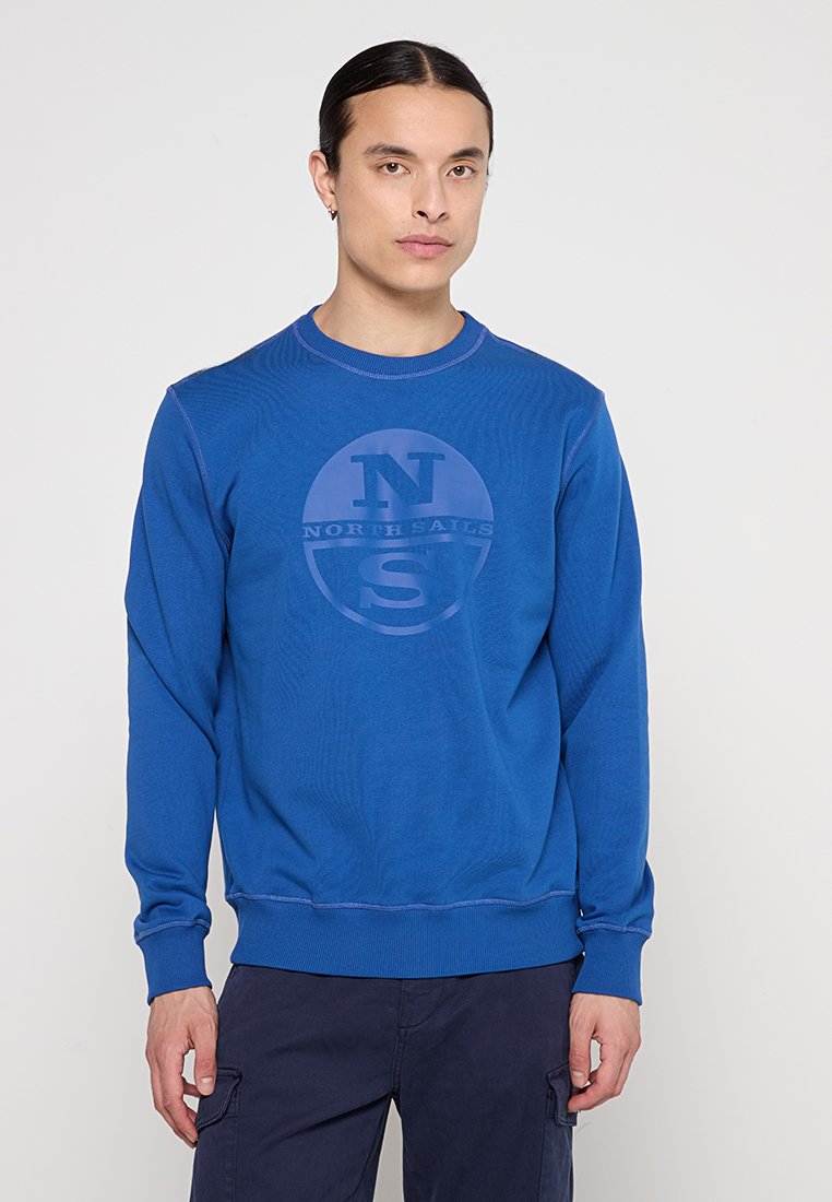 Felpa blu con colletto girocollo, caratterizzata da un logo circolare con "NORTH SAILS" e "N.S." al centro. Tessuto morbido, con polsini e orlo a costine.