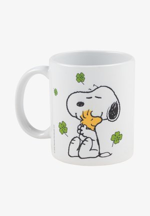 Weißer Keramikbecher mit einem Comic-Hund, der ein Stück Nahrung hält, umgeben von grünen vierblättrigen Kleeblättern. Glatte Textur, runde Form.