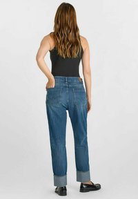 Jean en denim à coupe relaxée, de couleur bleu moyen, avec des manches retroussées et deux poches arrière. La vue arrière révèle une texture lisse et une étiquette à la taille.