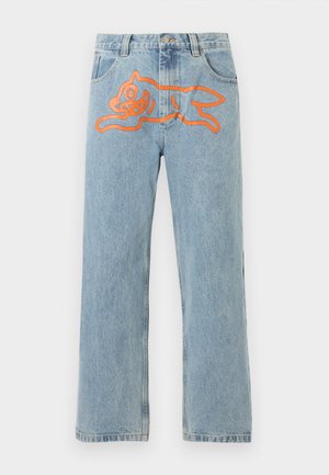 Lyseblå denimjeans med en stor orange grafik af en legesyg, tegneseriestil hund på forsiden ved taljeområdet.