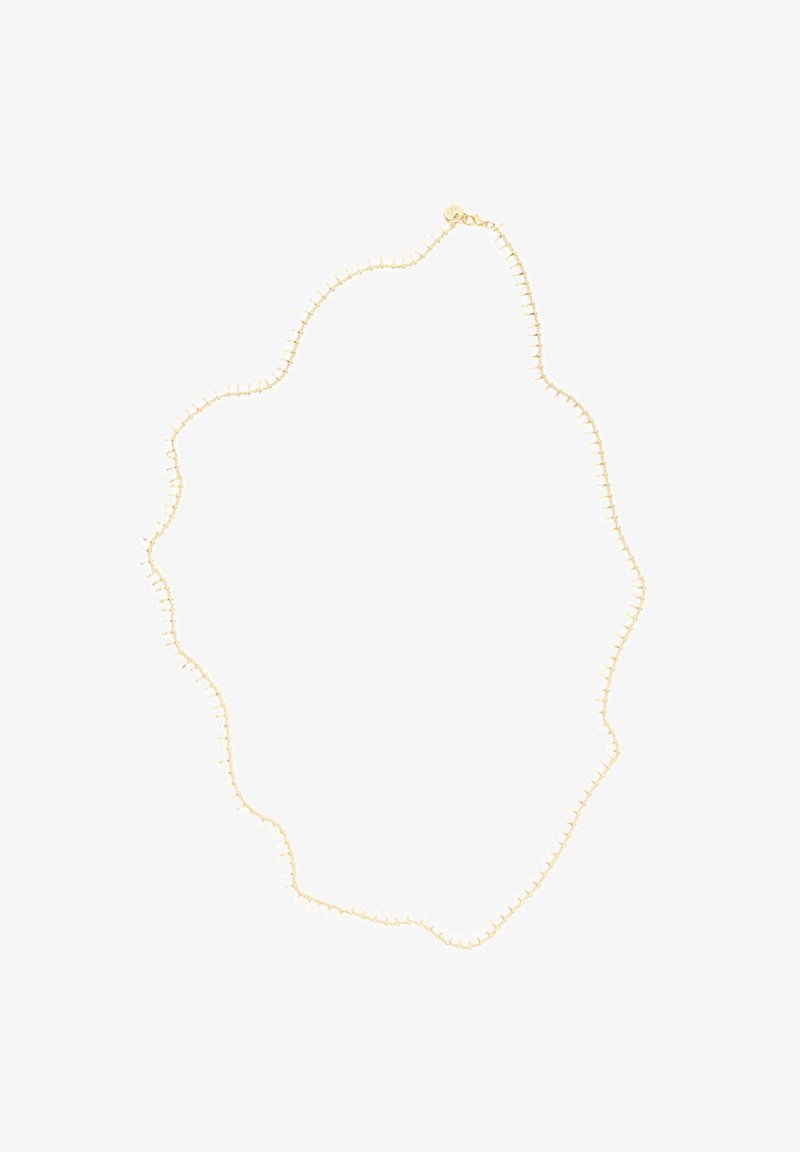 Goldfarbene Halskette mit einem gewellten Design, das entlang des Randes kleine runde Akzente aufweist, aus Metall mit einer glatten Oberfläche gefertigt.
