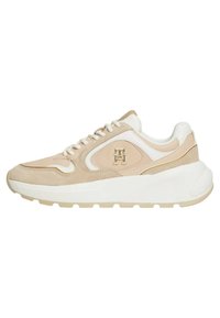 Sneaker beige e bianco con materiali in suede e pelle, punta arrotondata, design con lacci e dettagli del logo sul lato. Suola spessa bianca.