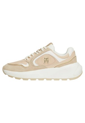 Sneaker beige e bianco con materiali in suede e pelle, punta arrotondata, design con lacci e dettagli del logo sul lato. Suola spessa bianca.