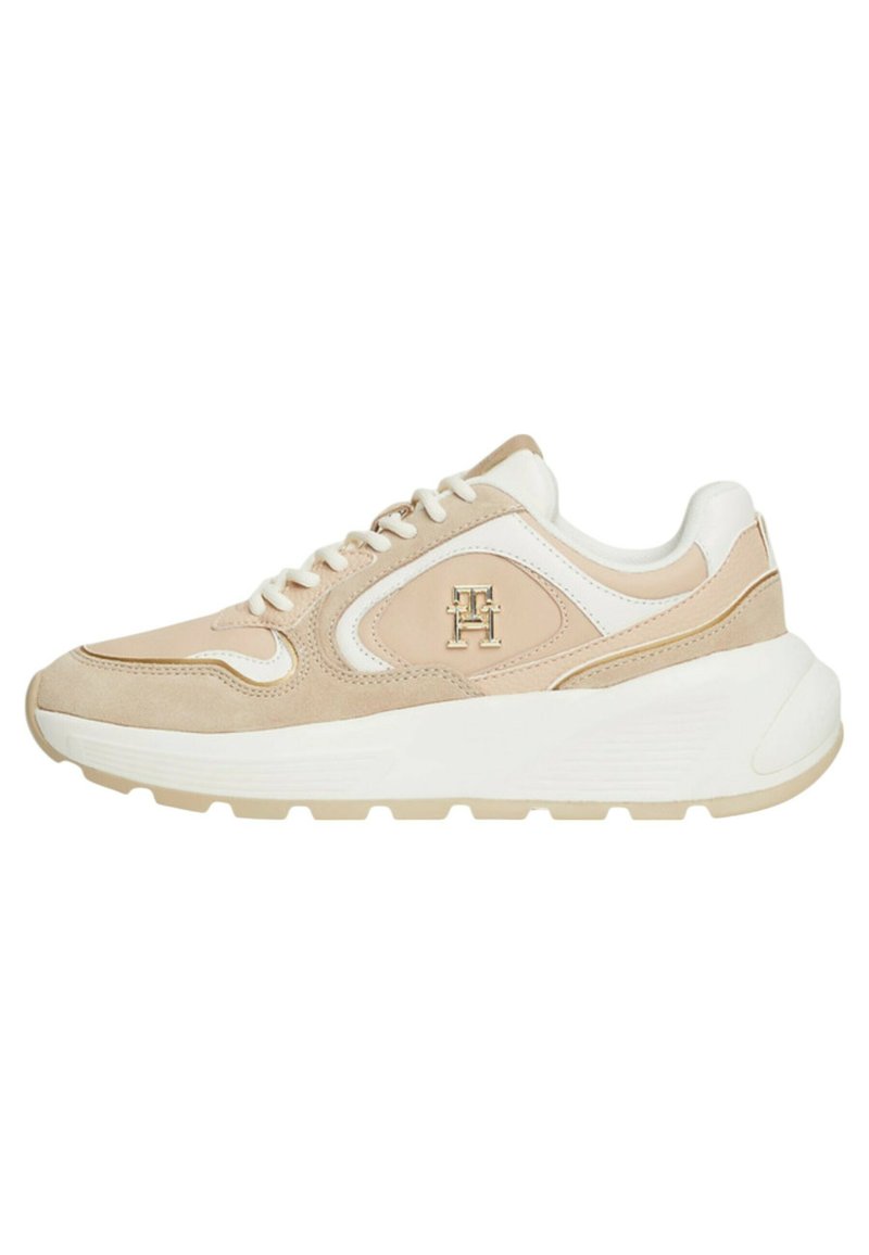 Sneaker beige e bianco con materiali in suede e pelle, punta arrotondata, design con lacci e dettagli del logo sul lato. Suola spessa bianca.