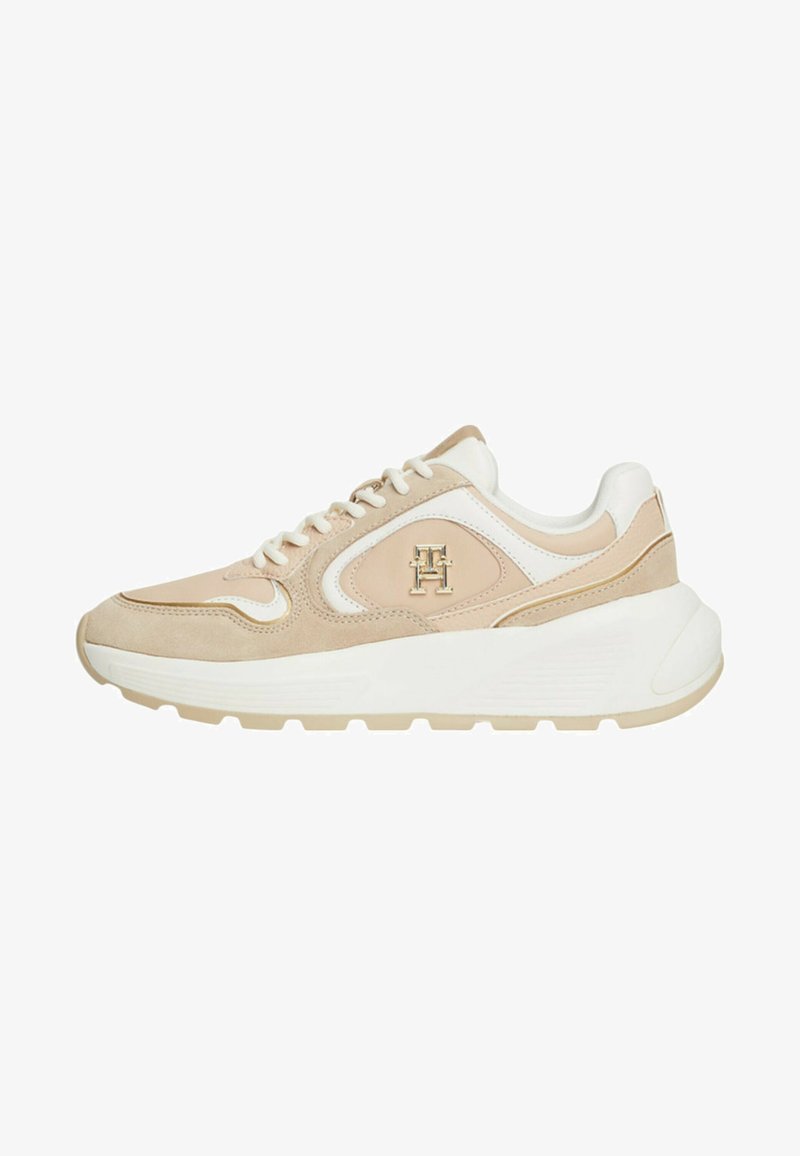 Sneaker beige e bianco con materiali in suede e pelle, punta arrotondata, design con lacci e dettagli del logo sul lato. Suola spessa bianca.