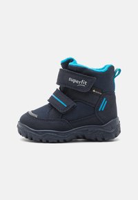 Bottes pour enfants bleu marine avec deux bandes Velcro réglables, doublure aqua contrastante, semelle en caoutchouc texturée et talon renforcé.