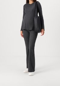 Grå ribbad långärmad topp som är kombinerad med matchande utsvängda byxor, kompletterad med en stilren svart väska. Modell iförd vita sneakers.