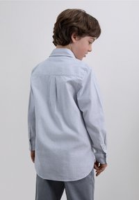 Camicia a maniche lunghe a righe in azzurro chiaro e bianco, con colletto abbottonato e orlo curvo, realizzata in tessuto liscio.