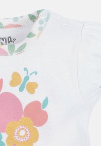 White toddler shirt with short puffed sleeves, featuring a colorful floral design in pink, yellow, and teal, and a patterned collar.