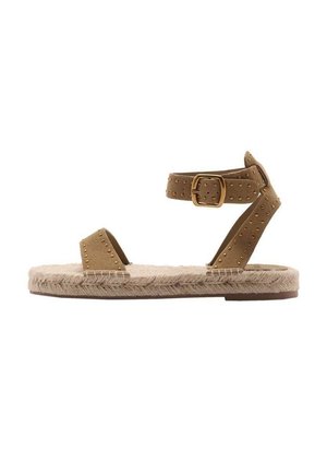 Beżowe zamszowe sandały z dwoma paseczkami ozdobionymi złotymi ćwiekami, zapięciem na klamrę oraz plecioną podeszwą z juty w beżowym kolorze.