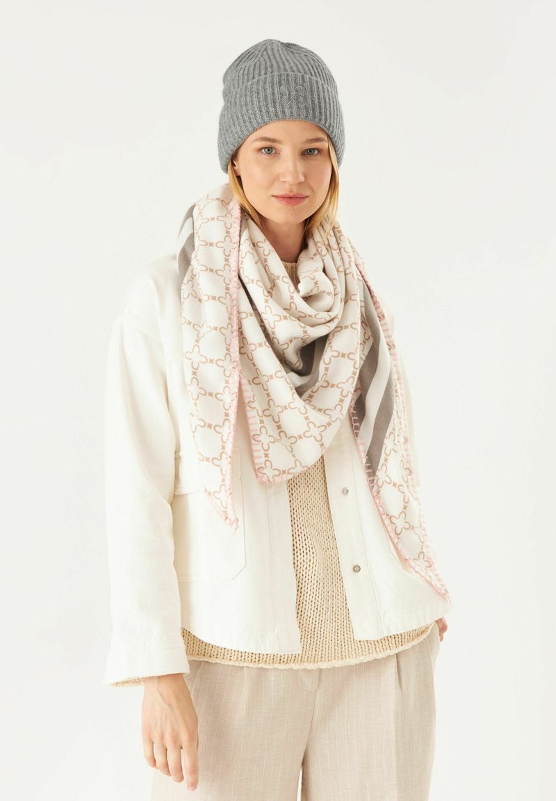 Gray knitted beanie, beige and pink patterned scarf, white jacket over a light sweater, cream wide-leg trousers, neutral color palette.