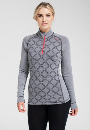 Grå, langærmet zip-up top med høj krave, prydet med et diamantmønster med gentaget tekst, accentueret af en rød lynlås. Glat tekstur.