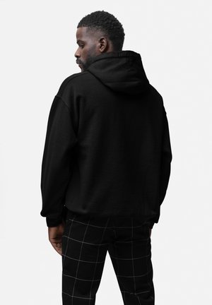 Sort hætte sweatshirt med en afslappet pasform, der har et struktureret stof og kengurulomme, parret med ternede sorte og hvide bukser.