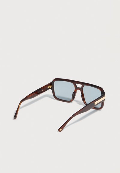 Ορθογώνια γυαλιά ηλίου με μοτίβο χελώνας, φακούς σε ανοιχτό γαλάζιο και χρυσές λεπτομέρειες στους βραχίονες, τοποθετημένα πάνω σε φωτεινή επιφάνεια.