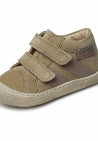 Tan suède kinderschoen met twee klittenbandsluitingen, rubberen zool en een bruine accentstreep. Textuur bovenwerk met stikdetails.