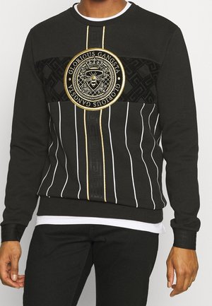 Zwarte sweatshirt met witte verticale strepen, een goudgerande bijenembleem en de tekst "Glorious Gangsta" op de borst.