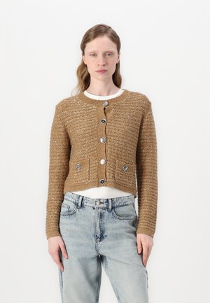 Cardigan accorciato in filato dorato testurizzato con scollatura rotonda, sei bottoni lucidi e due tasche frontali, abbinato a jeans azzurri chiari.