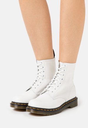Weiße Leder-Schnürstiefeletten mit runden Zehen, schwarzen Gummisohlen und gelben Nähtelementen. Glatte Textur und langlebiges Design.