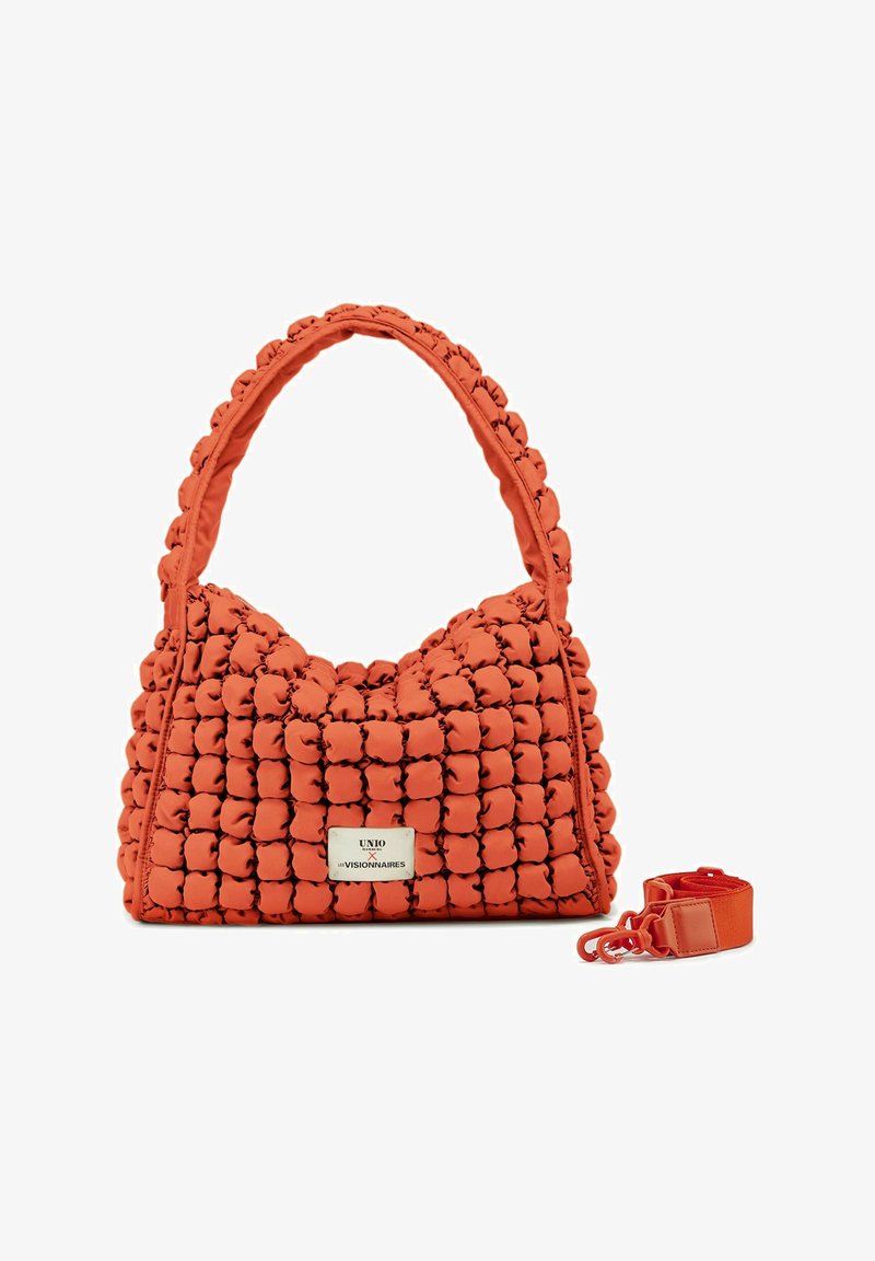 Oranje puffy handtas met een gestructureerd ontwerp, met een ronde vorm, een dikke schouderband en een afneembare rode schouderband.