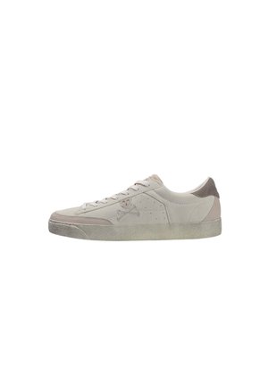 Zapatilla baja de ante beige claro con diseño de cordones y un sutil logotipo de calavera y huesos cruzados en el lateral.