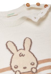 Sweter wełniany w kolorze kremowym z beżowym wzorem królika, z prążkowanym kołnierzem i trzema drewnianymi guzikami na ramieniu. Poziome paski poniżej.