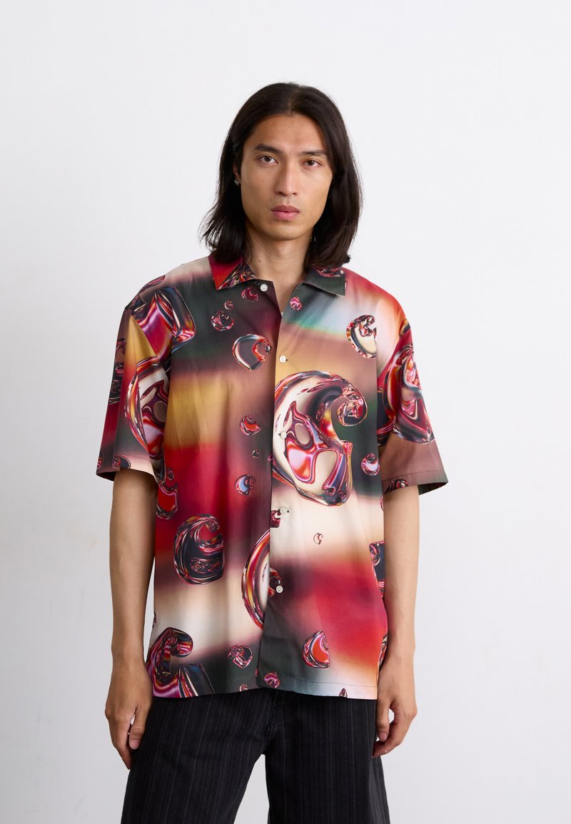 Chemise à manches courtes, à boutons, ornée d'un motif de bulles brillant dans des tons de rouge, marron et vert. Tissu lisse avec une coupe décontractée et un design de col.