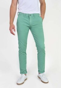 Lichtgroene katoen broek met een slim fit, voorzien van een knoopsluiting, voorzakken en opgerolde mouwen, gecombineerd met witte sneakers.