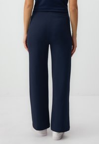 Navy blue wide-leg pants made of soft fabric, featuring a high waistband and a smooth texture, extending to the ankles with a clean finish.