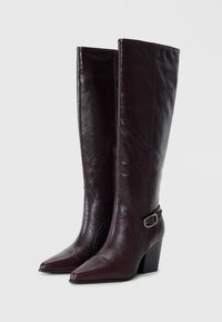 Purple leather knee-high boots with a pointed toe, block heel, and an adjustable buckle accent on the side. Textured finish.